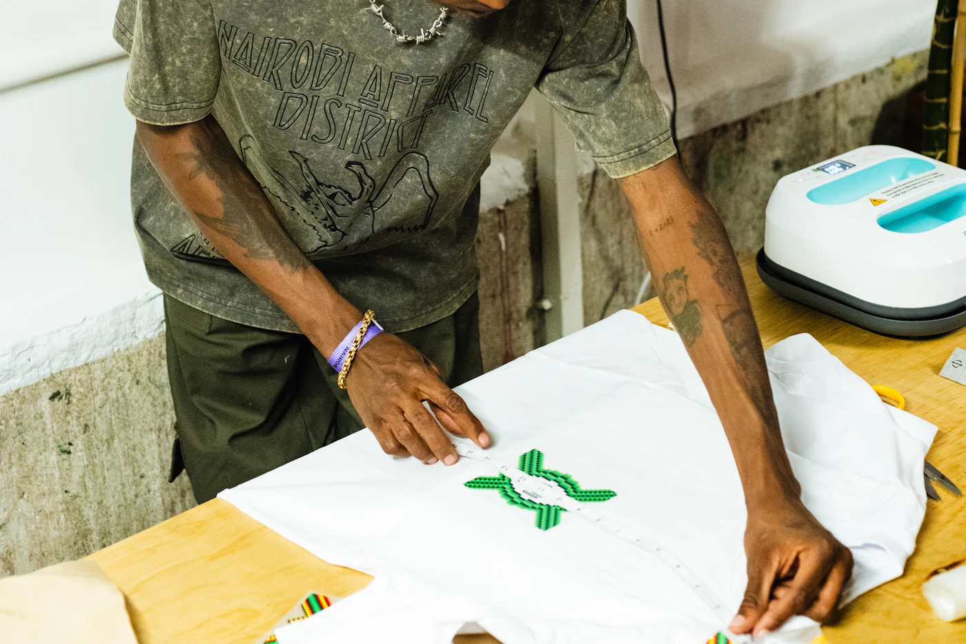 A printer lining up a design on a white t-shirt beside a heat press