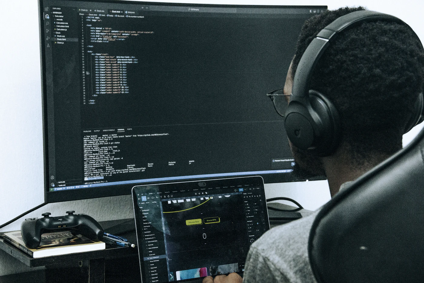 A developer in headphones writing code on a large monitor